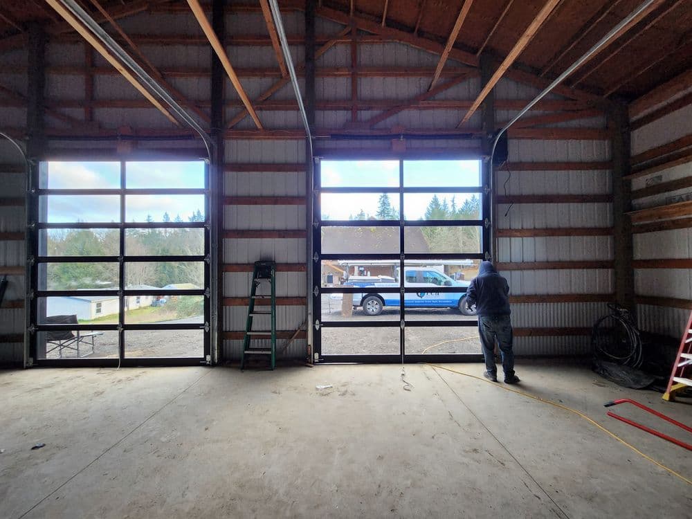 Interior view of a spacious garage with large windows and a man looking outside.