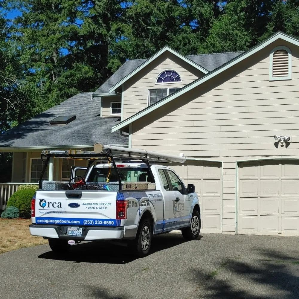 RCA garage door service truck parked in front of a residential home with a garage.